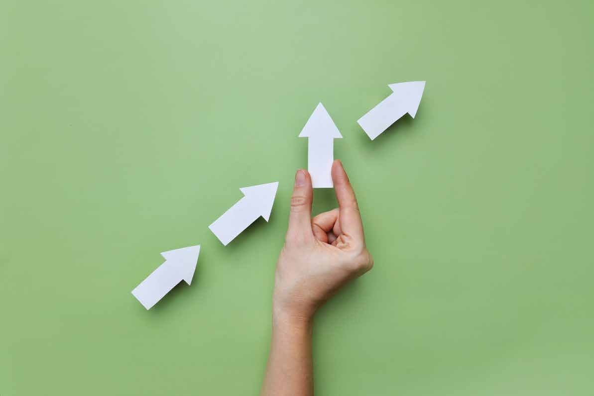 Hand arranging upward arrows on a green background